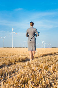 Rear view of businesswoman standing on field against sky