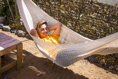 Smiling teenage boy lying in hammock