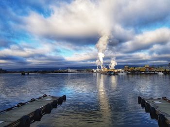 Smoke emitting from factory against sky