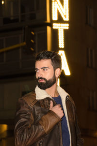 Young man standing in city at night