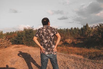 Rear view of man standing on field against sky