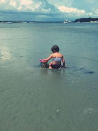 Rear view of boy on beach against sky