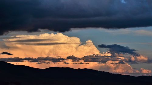 Scenic view of dramatic sky over silhouette mountain