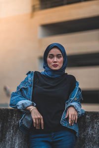 Portrait of young woman standing against wall