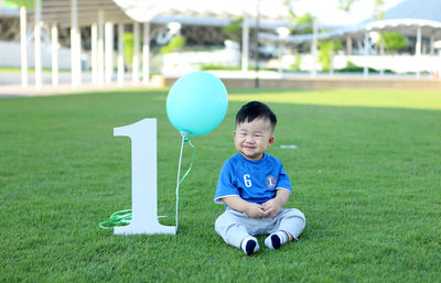 Cute boy with balloon and number 1 on grass