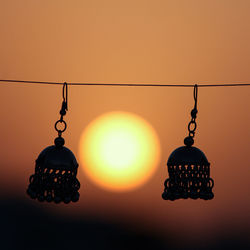 Close-up of illuminated lamp hanging against orange sky