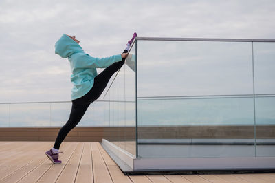 Side view of athlete stretching on glass railing