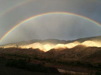 Scenic view of rainbow over mountains against sky