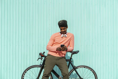 Man with bicycle standing against wall