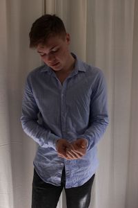 Young man standing against curtain