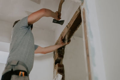 A young caucasian male builder clears a doorway using a crowbar.