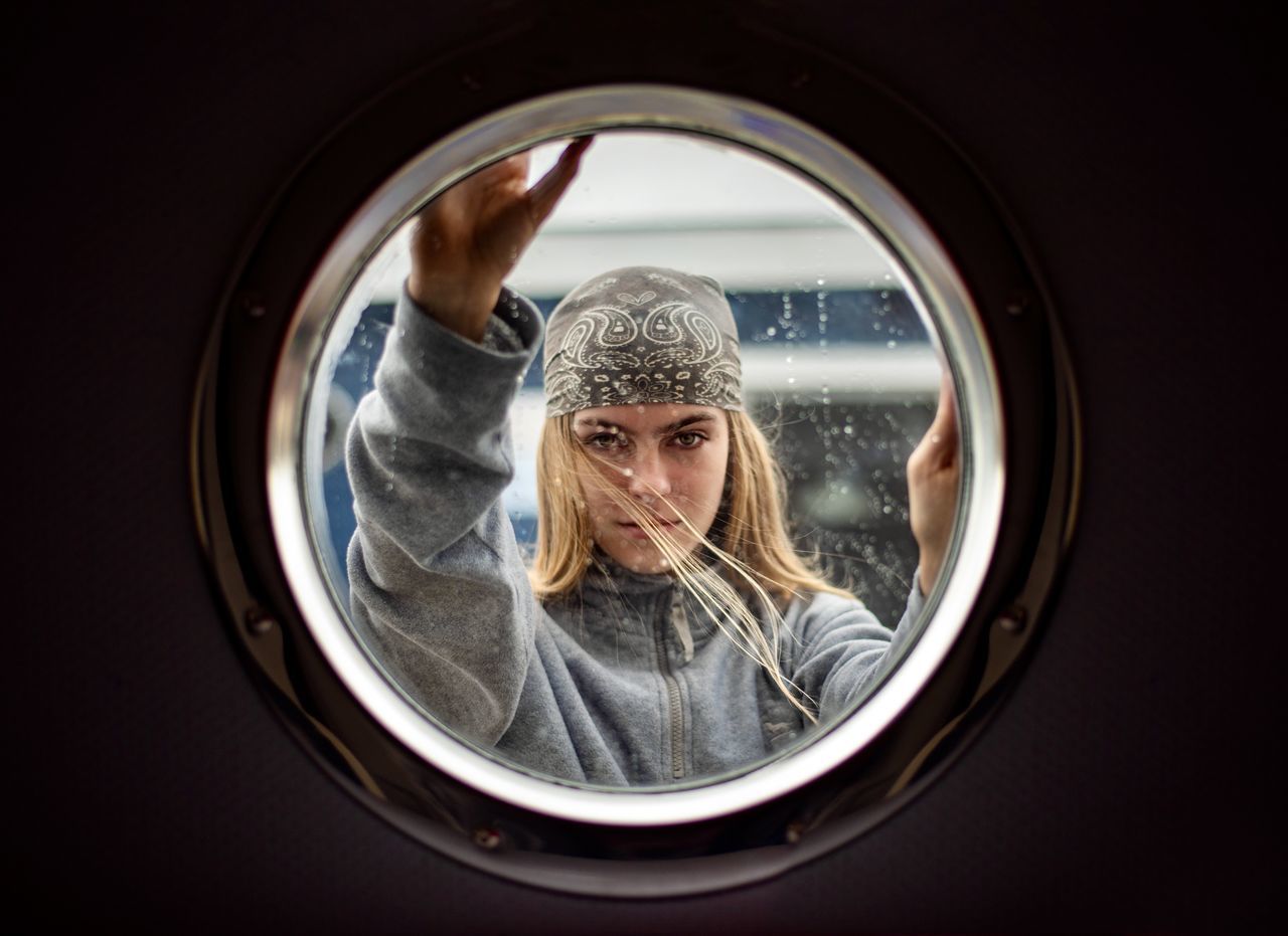 washing machine, laundry, appliance, one person, machinery, household equipment, circle, geometric shape, clothing, reflection, glass, shape, adult, window, indoors, lifestyles, portrait, looking, light, front view, cleaning, women, domestic life, young adult, housework, men, technology, laundromat