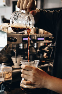 Close-up of hand pouring coffee cup