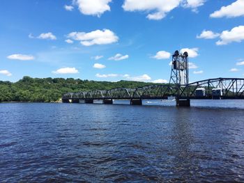 Bridge over river against cloudy sky