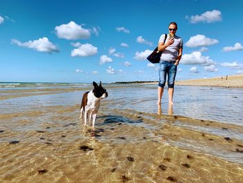 Full length of woman standing on beach against sky