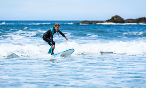 Full length of woman surfing in sea against clear sky