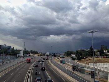 Cars on road against cloudy sky