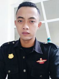 Portrait of young man standing against wall