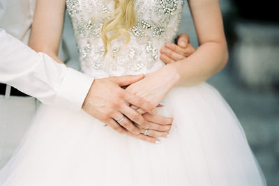 Midsection of bride holding wedding dress