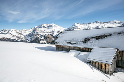 Snow covered house against mountains during winter