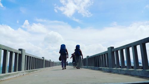 People on bridge against sky