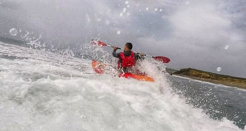 Man splashing water against sky