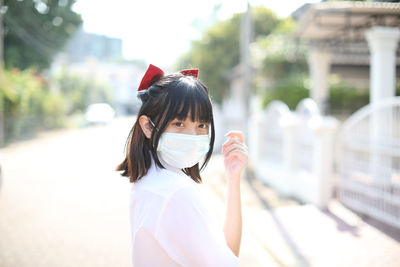 Portrait of young woman wearing mask standing outdoors