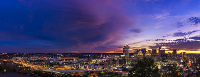 High angle view of city lit up against cloudy sky