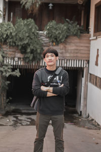 Portrait of young man standing against building