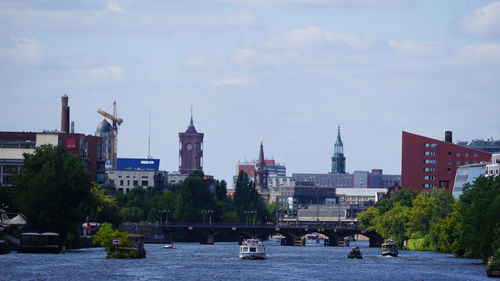 Boats in river against buildings in city