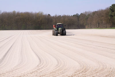 Tractor on road amidst field against sky