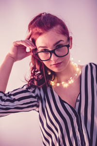 Young woman with illuminated string light against gray background