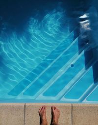 Low section of person standing by swimming pool