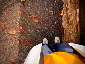 Low section of people standing by autumn leaves in city