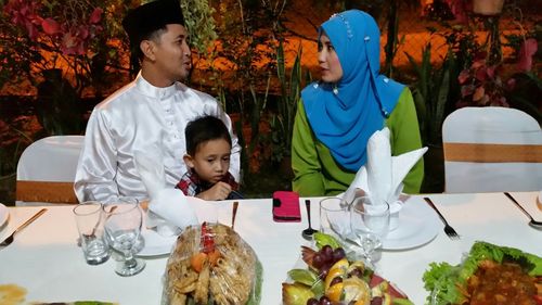 Full length of father and daughter sitting on table at home