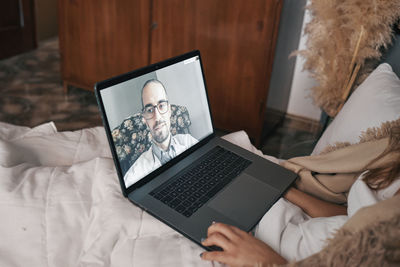 Young woman talking to doctor on video call at home