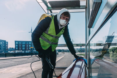 Portrait of worker cleaning bench in city