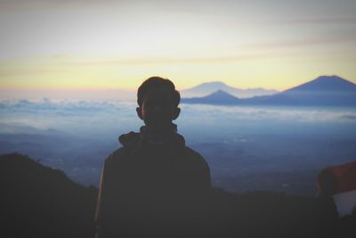 Rear view of silhouette man looking at mountains against sky