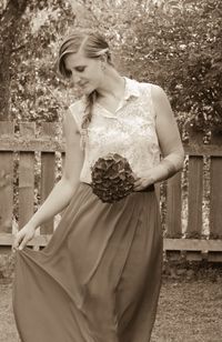 Midsection of woman holding flowers standing by railing