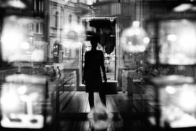 Woman walking on illuminated street at night