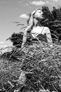 Young woman looking at camera on field against sky