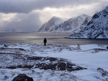 Man standing on snow covered landscape against sky