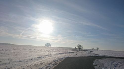 Tire tracks on sand against sky during winter