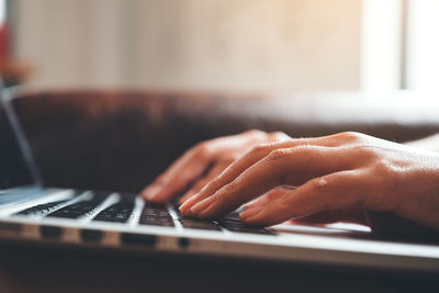 Cropped hands of person using laptop