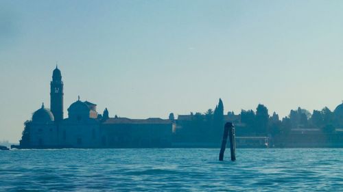 Man standing on building by sea against clear sky