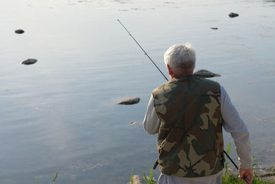 Rear view of man with dog on lake