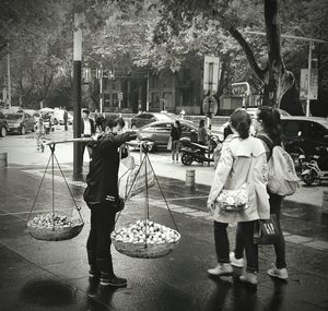 Rear view of girls walking on sidewalk in city