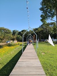 Footpath amidst trees on field against clear sky