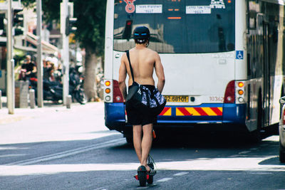 Rear view of shirtless man standing on road