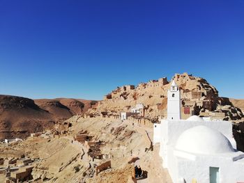 Panoramic view of buildings and mountain against blue sky